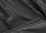 A close-up of draped black leather fabric with a smooth, pebbled texture and soft folds.