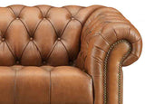 Brown leather armchair with tufted backrest and nailhead trim on a white background