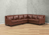 Brown leather sectional sofa in a room with a gray wall and wooden floor.