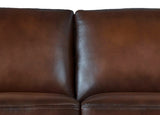 Close-up of a brown leather sofa with a plain background