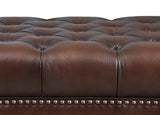 Close-up of a brown leather sofa with tufted design and nailhead trim.