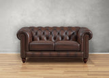 Brown leather sofa against a gray wall on a wooden floor