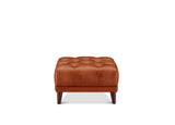 A square tufted leather ottoman in a warm cognac brown, supported by four dark wooden legs, shown against a plain white background.