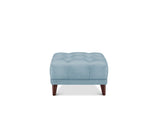 A light blue tufted ottoman with dark brown wooden legs, shown from the front on a solid white background.