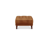 A square tufted leather ottoman in a warm cognac brown, supported by four dark wooden legs, shown against a plain white background.