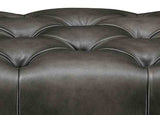 Close-up of a dark brown leather sofa with tufted backrests.