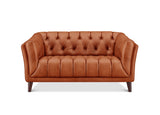 A classic tufted leather loveseat sofa in a warm cognac brown color, featuring dark wood legs, shown against a plain white background.