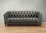Brown leather sofa against a gray wall on a wooden floor