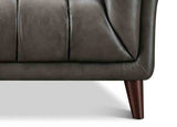 Close-up of a dark gray leather sofa with wooden legs on a white background