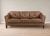 A three-seat brown leather sofa with diamond-quilted back cushions, shown in a studio setting with a textured beige wall and light wood floor.