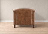 A brown leather armchair with a high back and rolled arms, shown from the rear in a minimalist room with light wood flooring and a textured beige wall.