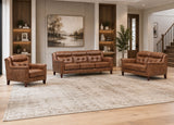 A three-piece brown leather furniture set consisting of a loveseat, a three-seat sofa, and an armchair, arranged on a large distressed beige rug in a modern living room with wood floors and built-in shelves.