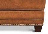 Close-up of a brown leather armchair with studded details on a white background