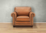 Brown leather armchair against a gray wall on a wooden floor