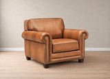 A classic brown leather armchair with rolled arms, nailhead trim, and dark wooden legs, set against a neutral beige wall and light wood floor.