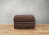 Brown ottoman on a wooden floor with a gray wall background