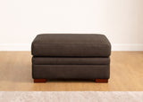 Brown ottoman on a wooden floor with a white wall background