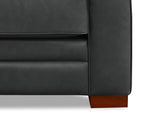 Close-up of a black leather sofa corner with a wooden leg on a white background