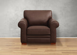 Brown leather armchair on a wooden floor with a gray wall background
