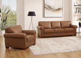 Brown leather sofa and armchair in a living room setting with a lamp and artwork.