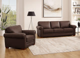 Brown leather sofa and armchair set in a living room with a lamp and artwork.