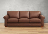 Brown leather sofa against a gray wall on a wooden floor