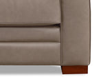 Close-up of a beige leather sofa corner with a wooden leg on a white background