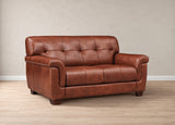 A brown leather loveseat sofa with tufted back cushions and rolled arms, shown in a studio setting with a beige wall and light wood floor.