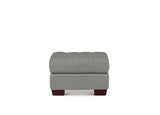 A modern square ottoman upholstered in light gray fabric, featuring a tufted back cushion and dark reddish-brown wooden legs, shown against a plain white background.