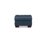 A modern tufted ottoman in dark blue leather with dark brown wooden legs, shown against a plain white background.