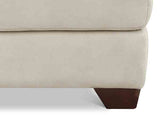 Close-up of a beige sofa with a brown leg on a white background