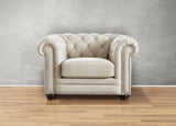 Beige armchair with tufted backrest on a wooden floor against a gray wall
