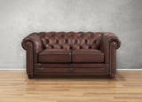 Brown leather sofa against a gray wall on a wooden floor