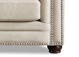 Close-up of a beige sofa with nailhead trim on a white background