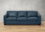 Blue leather sofa on a wooden floor with a gray wall background