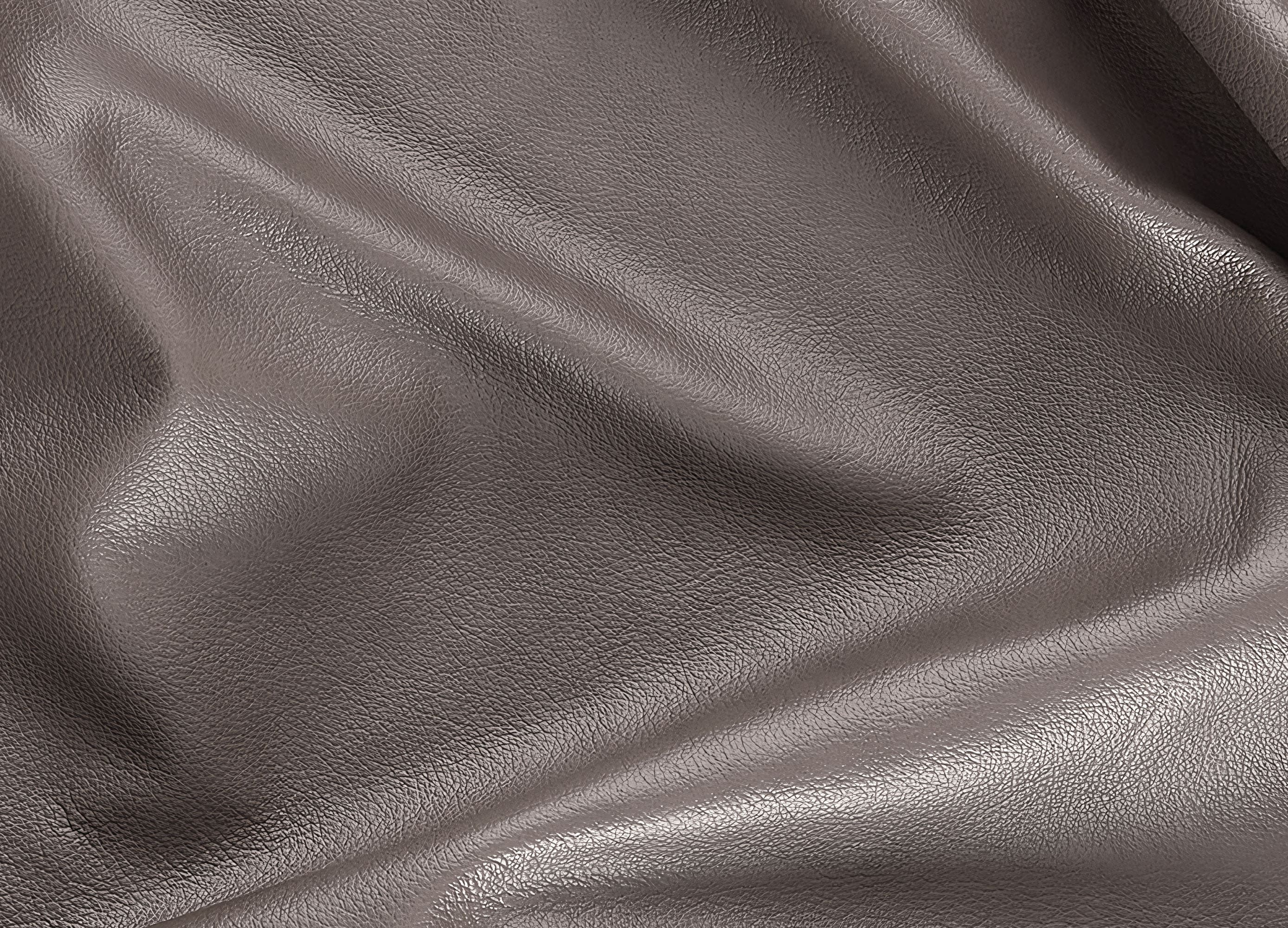 A close-up of draped pebbled leather fabric in a taupe-brown color, showing the texture and soft folds.
