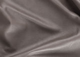 A close-up of draped pebbled leather fabric in a taupe-brown color, showing the texture and soft folds.
