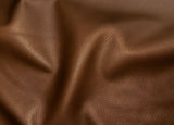 A close-up of draped brown pebbled leather fabric showing its texture and soft folds.