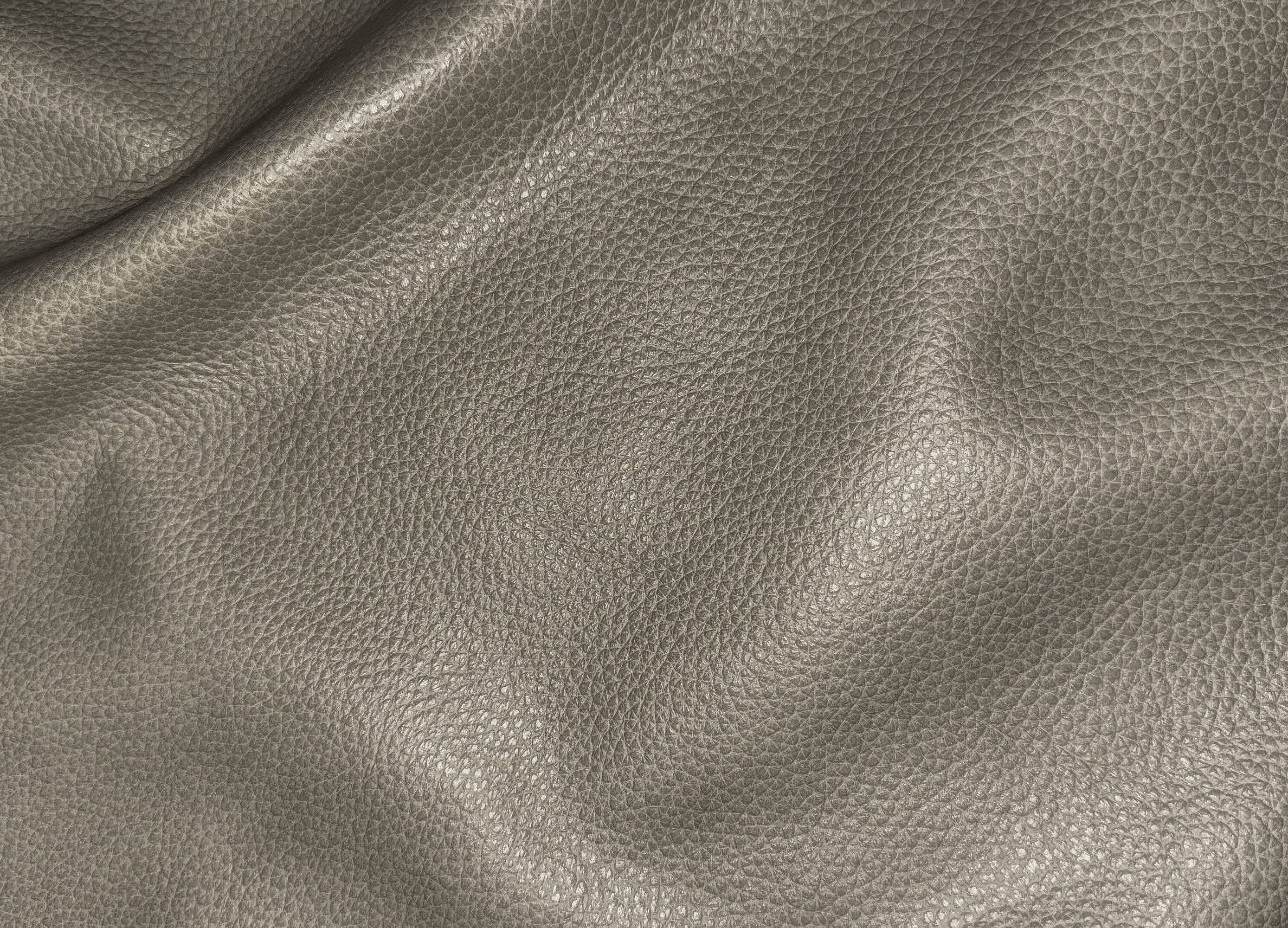 A close-up of textured leather material in a warm taupe-gray color, showing the pebbled grain and soft folds.