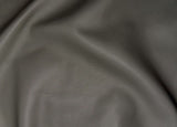 A close-up of dark gray pebbled leather fabric with soft folds and a smooth texture.