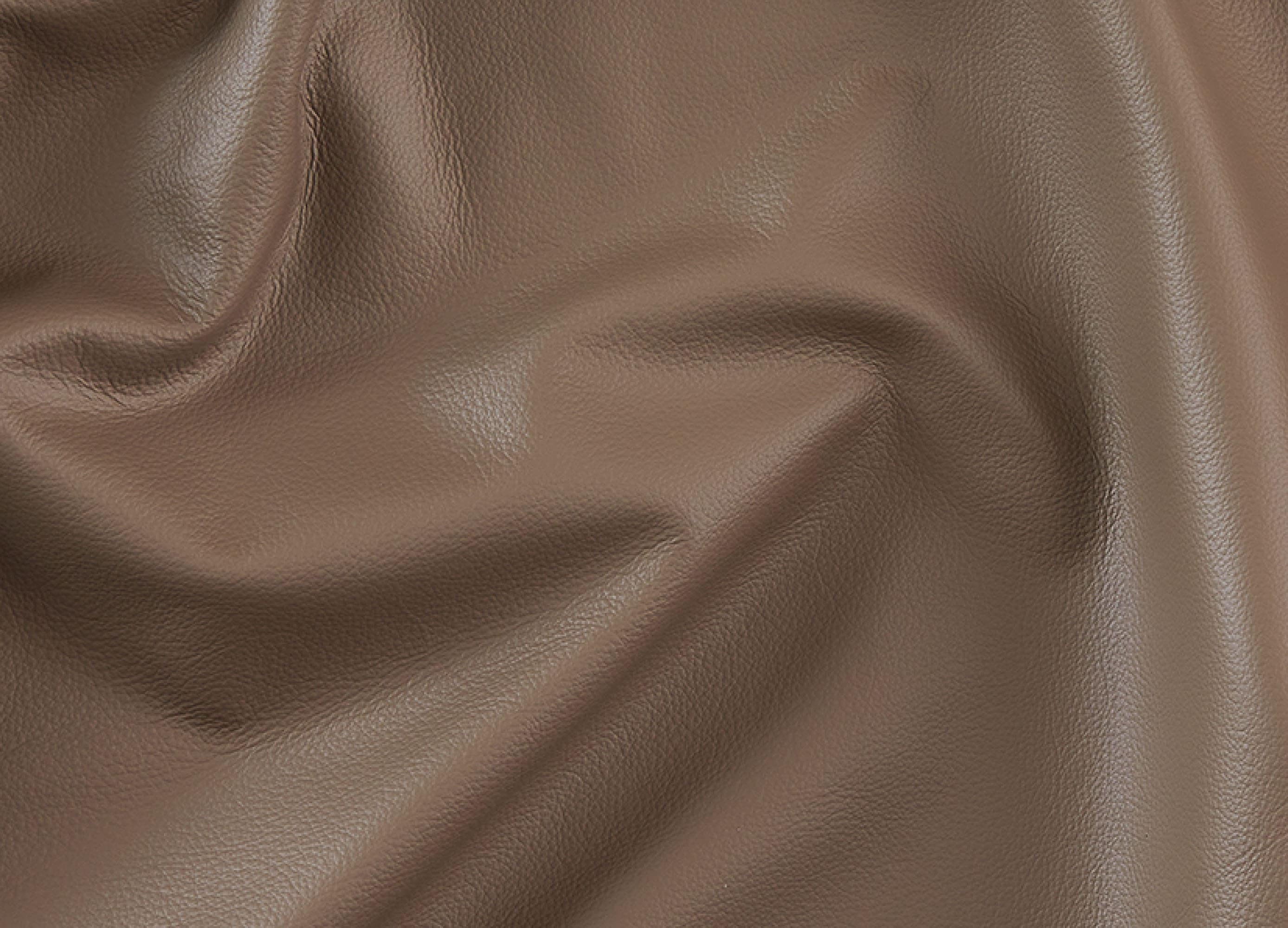 A close-up of draped brown faux leather fabric with a pebbled texture and soft folds.