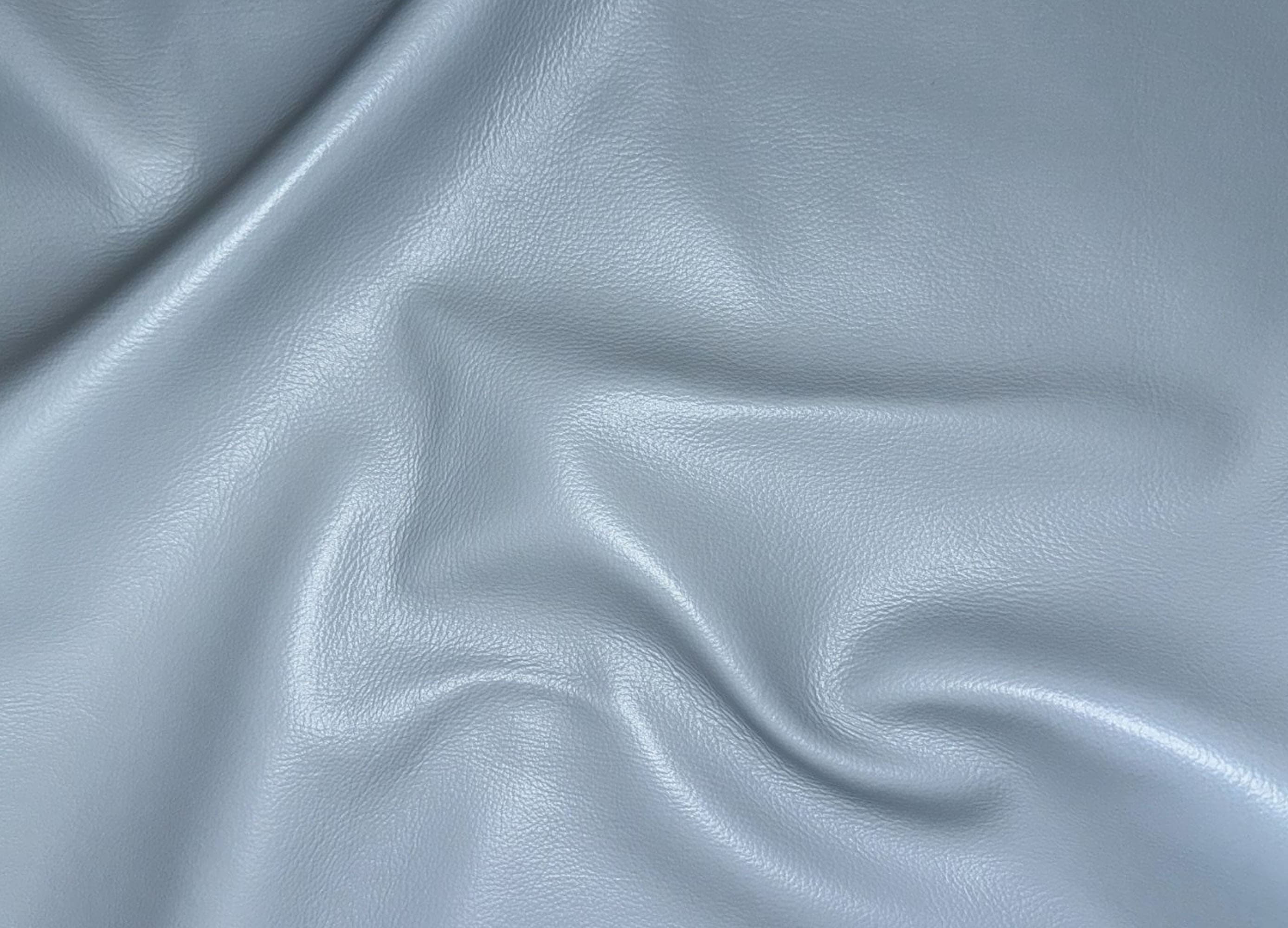 A close-up of draped light gray faux leather or vinyl fabric with a smooth, slightly glossy texture.