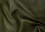 A close-up of dark olive green pebbled leather fabric with soft folds and shadows.