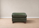 A dark green leather ottoman with stacked cushioned seats and dark wooden legs, positioned against a neutral beige wall and light wood floor.