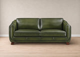 An olive green leather loveseat sofa with a two-seater configuration, shown in a studio setting with a textured beige wall and light wood flooring.