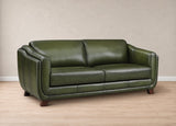 An olive green leather loveseat sofa with dark wood legs, shown in a studio setting with a beige textured wall and light wood floor.