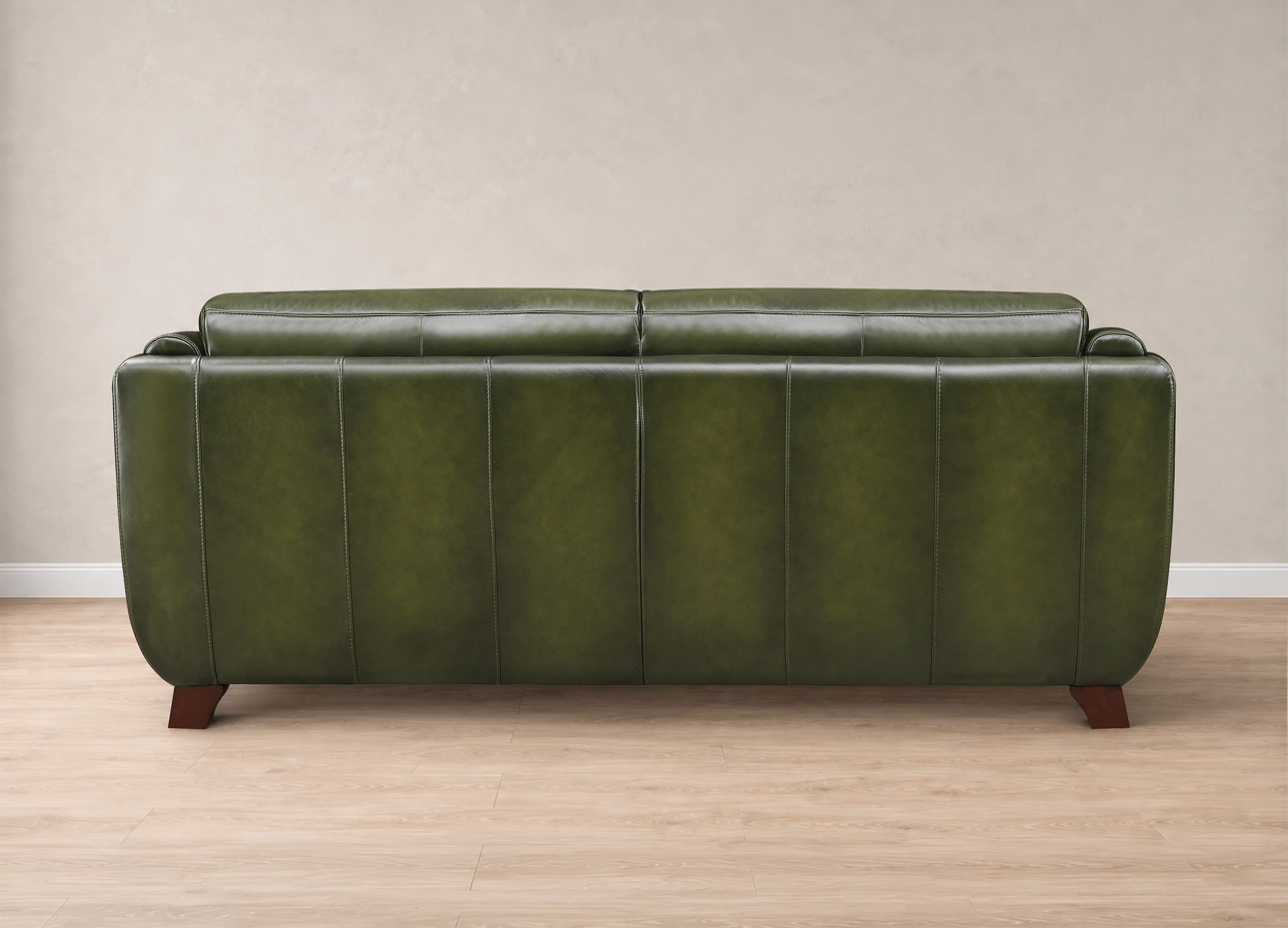 An olive green leather loveseat sofa with vertical channel tufting and dark wood legs, shown from the back in a minimalist room setting with a beige wall and light wood floor.