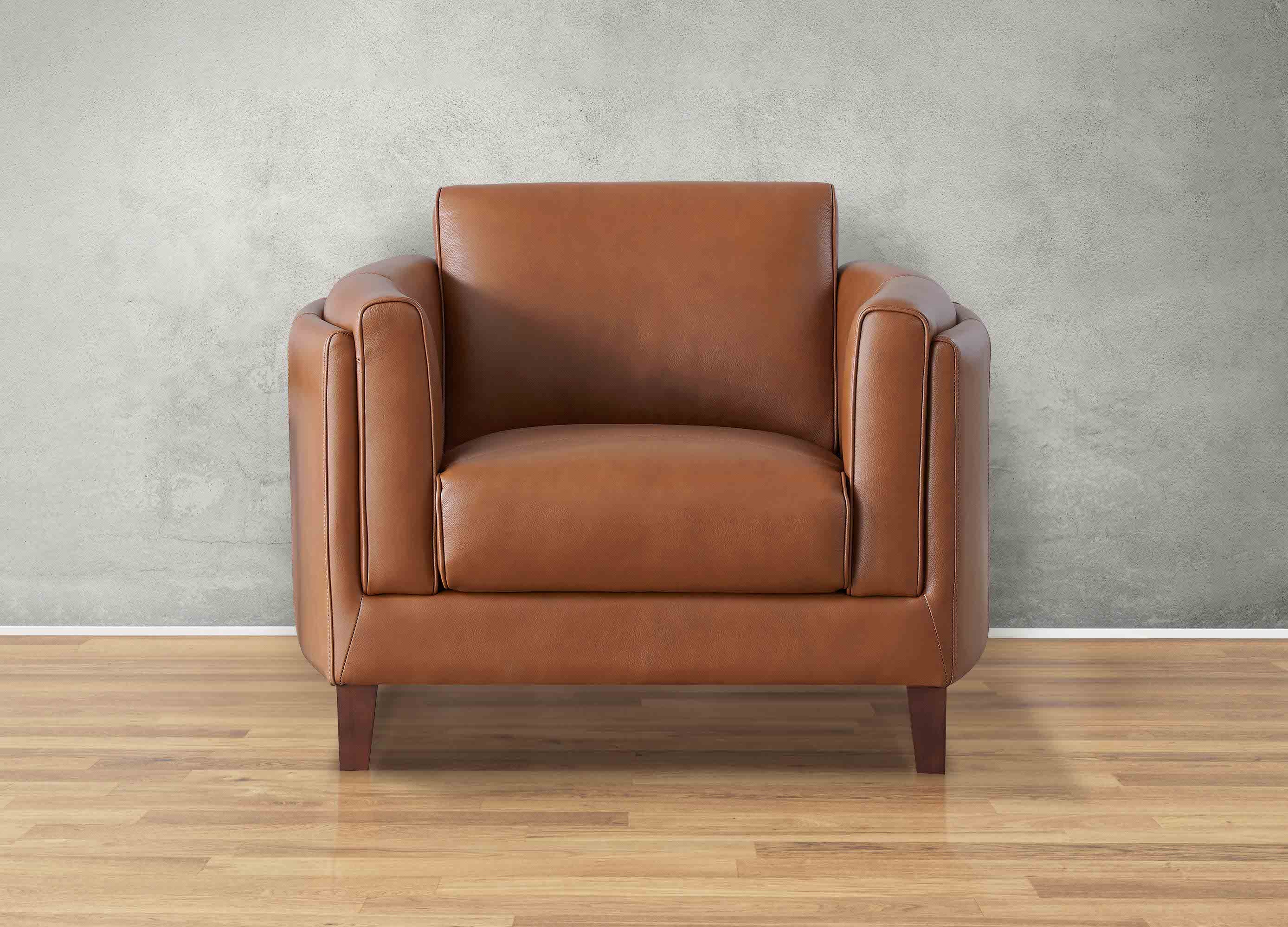 Brown leather armchair against a gray wall on a wooden floor