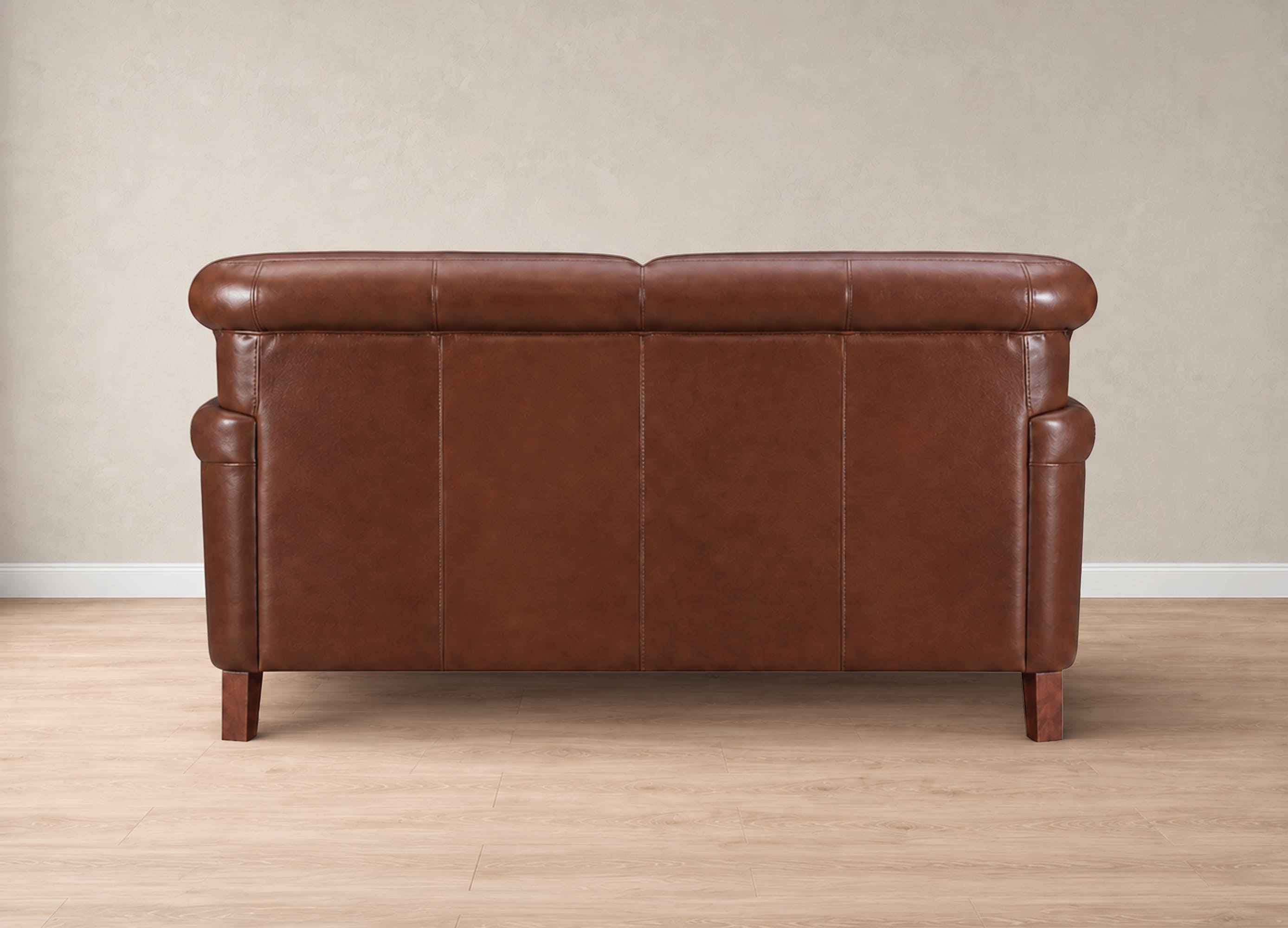 A brown leather loveseat sofa shown from the back, featuring a tufted backrest, rolled arms, and wooden legs, set against a neutral beige wall and light wood floor.