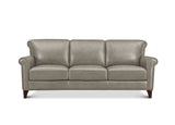 A three-seat leather sofa in a light taupe-gray color, featuring rolled arms, nailhead trim, and dark wood legs, shown against a plain white background.